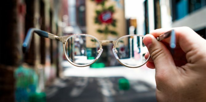 Ruka držící brýle na ulici
