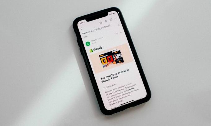 iPhone proti bílému povrchu zobrazující e-mail na obrazovce